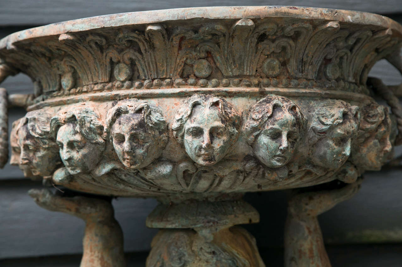 each putto holds an 8 inch  by 17 inch  planter, decorated with  lead forms , ring handles and female heads
each putto  has a quiver  and a strap across his  torso.
at the waist is a  ram's fleece with the ram's head  on the right backside. on the