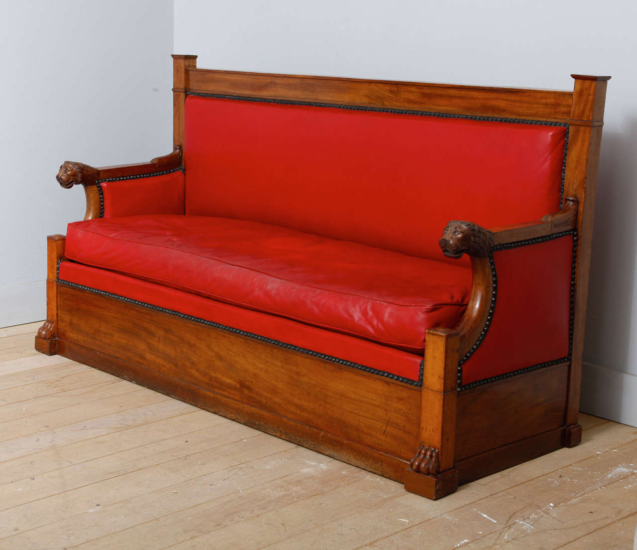 Mahogany Empire settee with upholstery in red leather lined with a black spiked border. The elbow-rests are ending in a carved lion’s head and the front legs in lion paw feet. 

H. 102,50, W. 183 cm, D. 65 cm