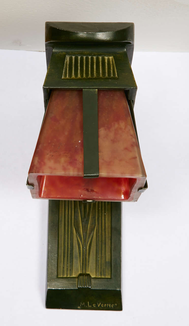 Pair of sconces with a green patinated bronze structure. Pink orange colored glass shades. Signed 'M. Le Verrier'. French work, circa 1920-1930. Wired for European use.