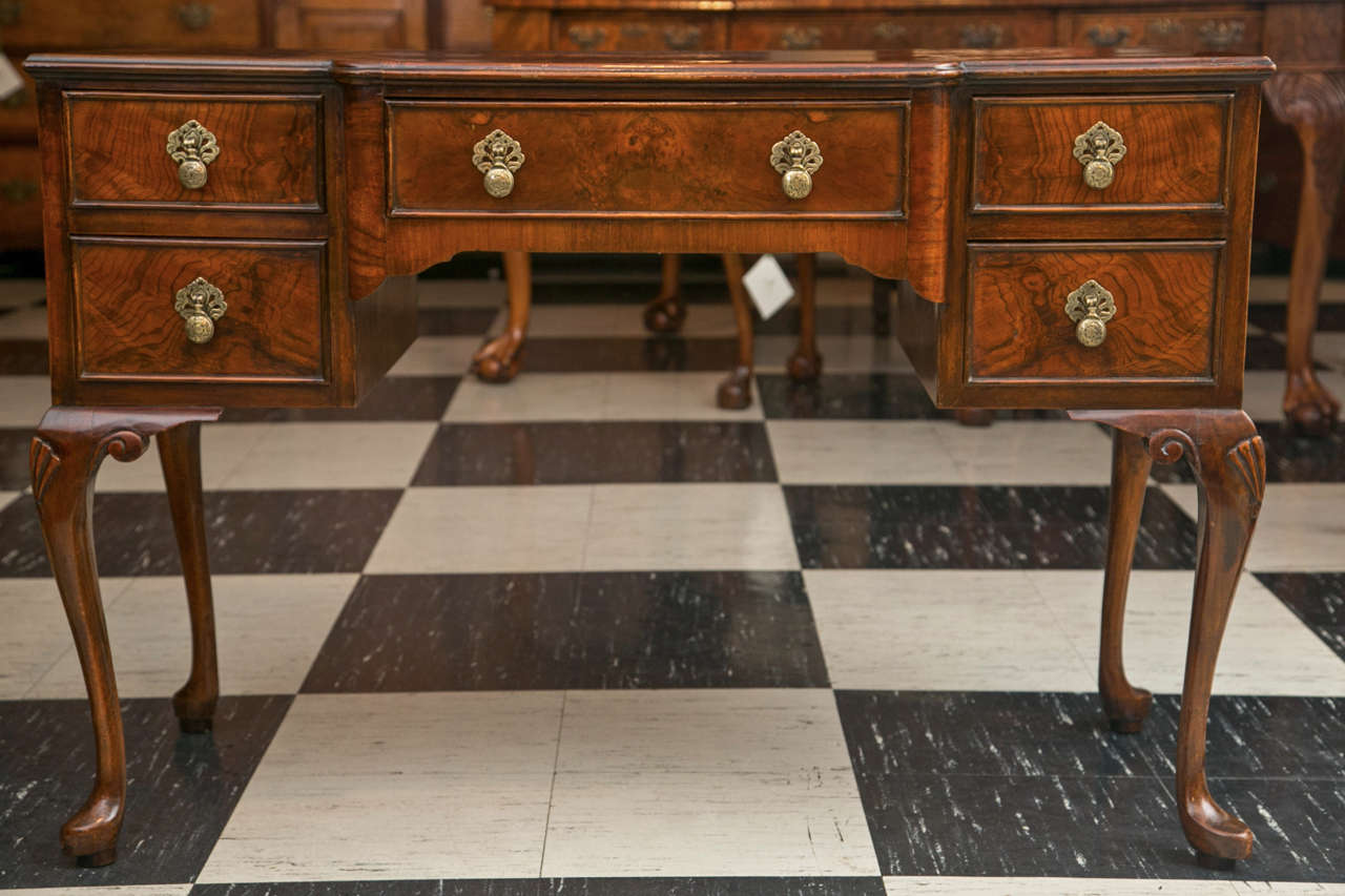 Covered in a deeply figured walnut burl, this shaped front lowboy would do equally as well as a dressing table as it would occasional table or console. With its shell carved knees on cabriole legs ending in pad feet, it has a profile that is as