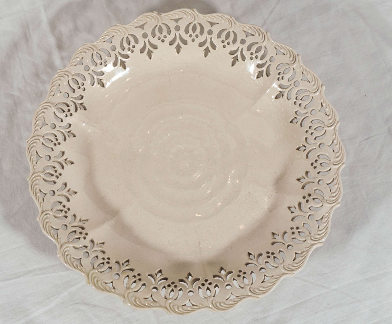A pair of Leeds Pottery creamware dishes the center of each dish with the impressed design of a rose, and the rims pierced with a band of openwork design. The dishes are thinly potted. The edges decorated with raised feather edge borders. They will