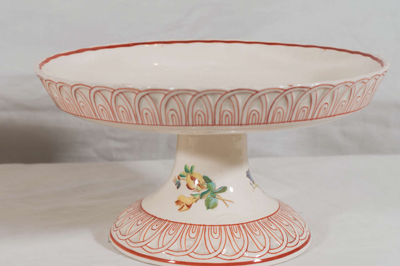 A pair of lovely creamware cake stands each painted with a single yellow daisy.
The borders and base are decorated with a continuous design of interconnected red arches.