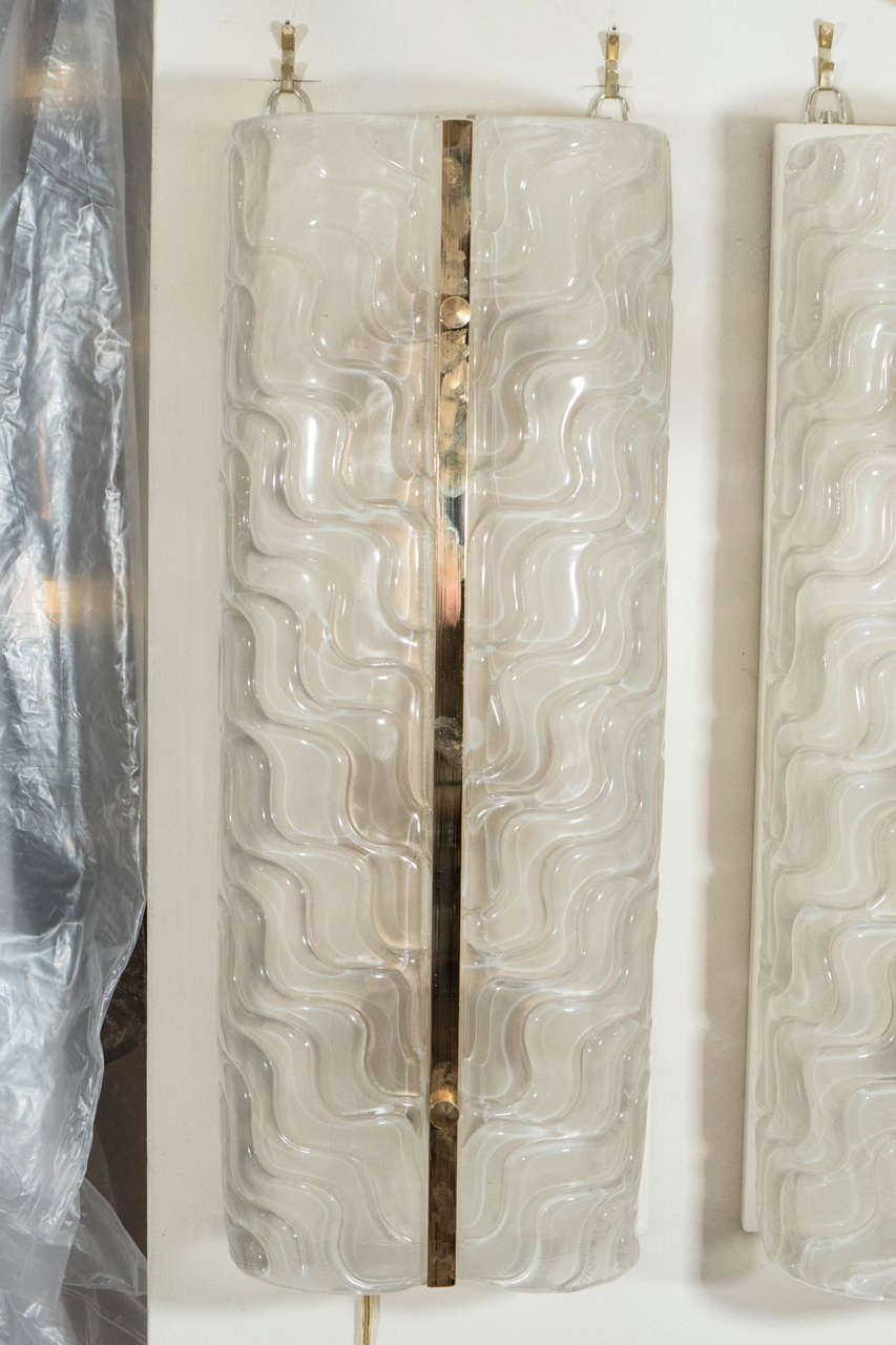 Pair of large rectangular undulating textured glass sconces with brass details.