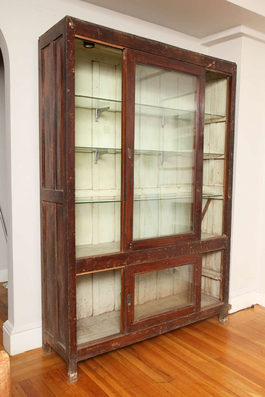 Glass-front bookcase with painted interior and glass shelves, from India. Original hardware.