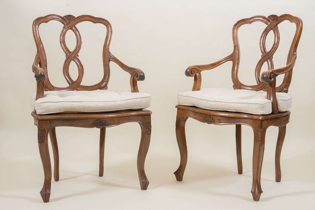Pair of 18th century style Italian walnut armchairs. Good carved details with pegged joinery. Hand caned seats with older custom fit cotton weave cushions. Sturdy and large-scale, circa 1920.
