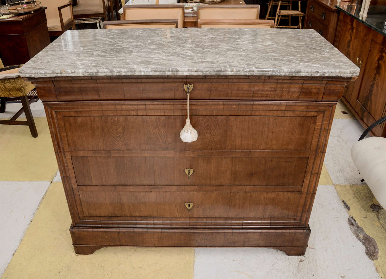 FIGURED MAHOGANY CHEST TOPED WITH MOTTLED GREY MARBLE-- INCISED MOULED EDGE. 4 DRAWERS--THE TOP OGEE MOULDED FRONT THE OTHER 3 FLAT FRONTED FRAMED BY DECORATIVE MOULDING--FLAT KICKBOARD BASE RAISED ON LOW BRACKET BASE--- SHIELD SHAPED ESCUTCHEON