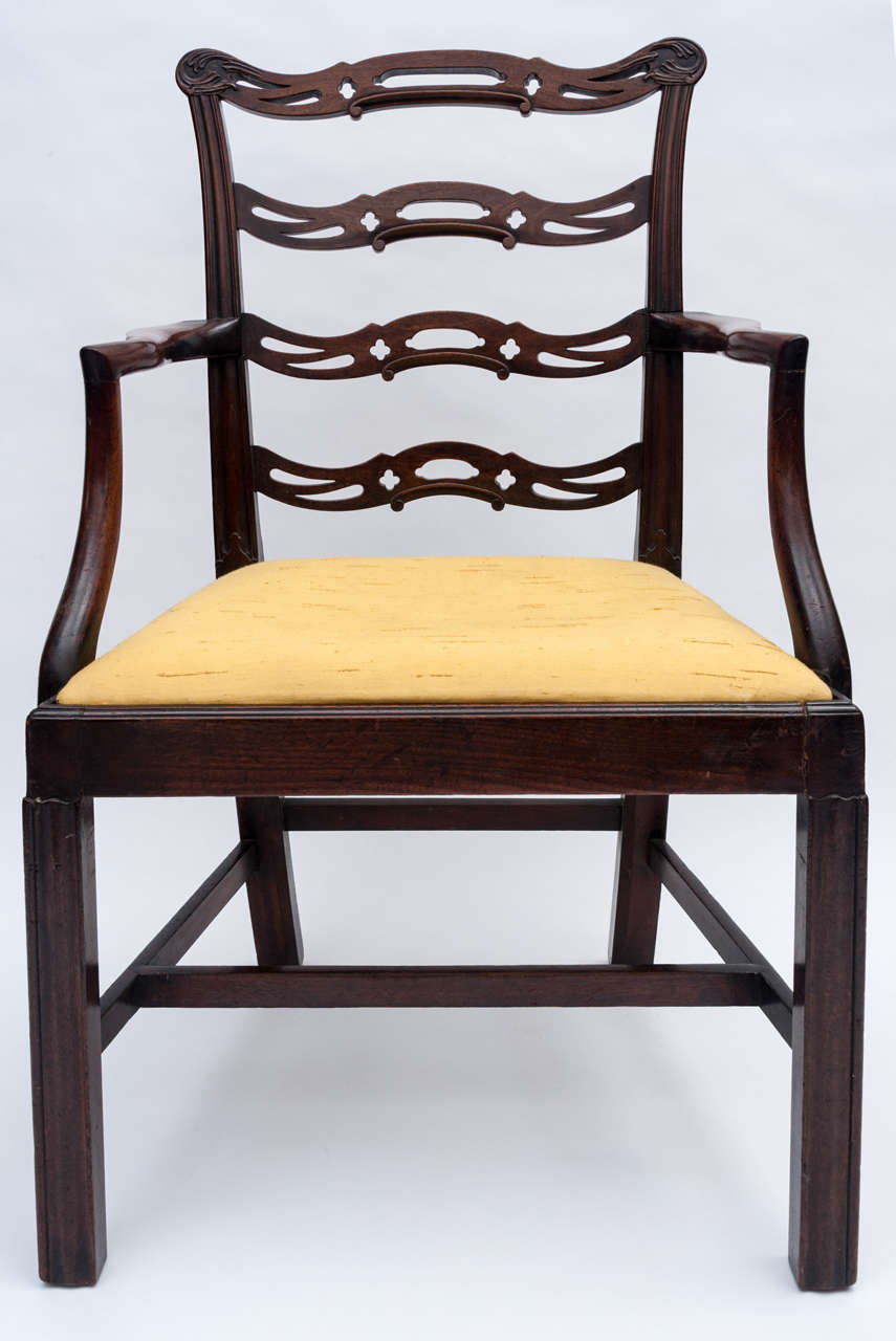 A Georgian mahogany 'Chippendale' elbow chair; the shaped top rail with acanthus carved corners, the pierced ladder back supported by molded uprights, the shaped arms terminating with a drop in seat, raised on molded front legs.  Lovely color.