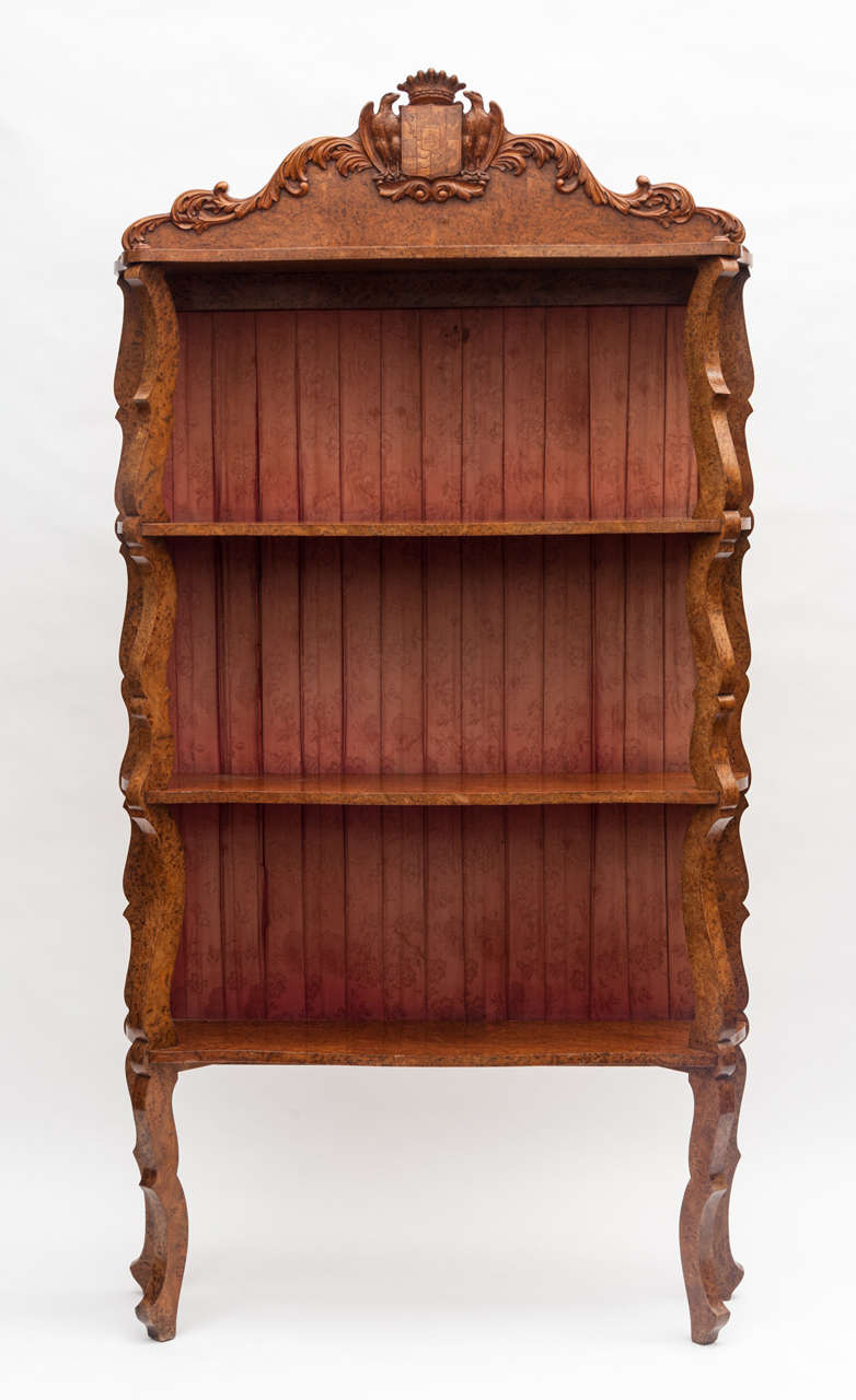 Mid-19th century unusual Continental amboyna étagère or standing shelves; the shaped top with carved acanthus scrolling, centred by an interesting coat of arms flanked by 2 eagles and a coronet. The four shaped shelves on scrolled supports all