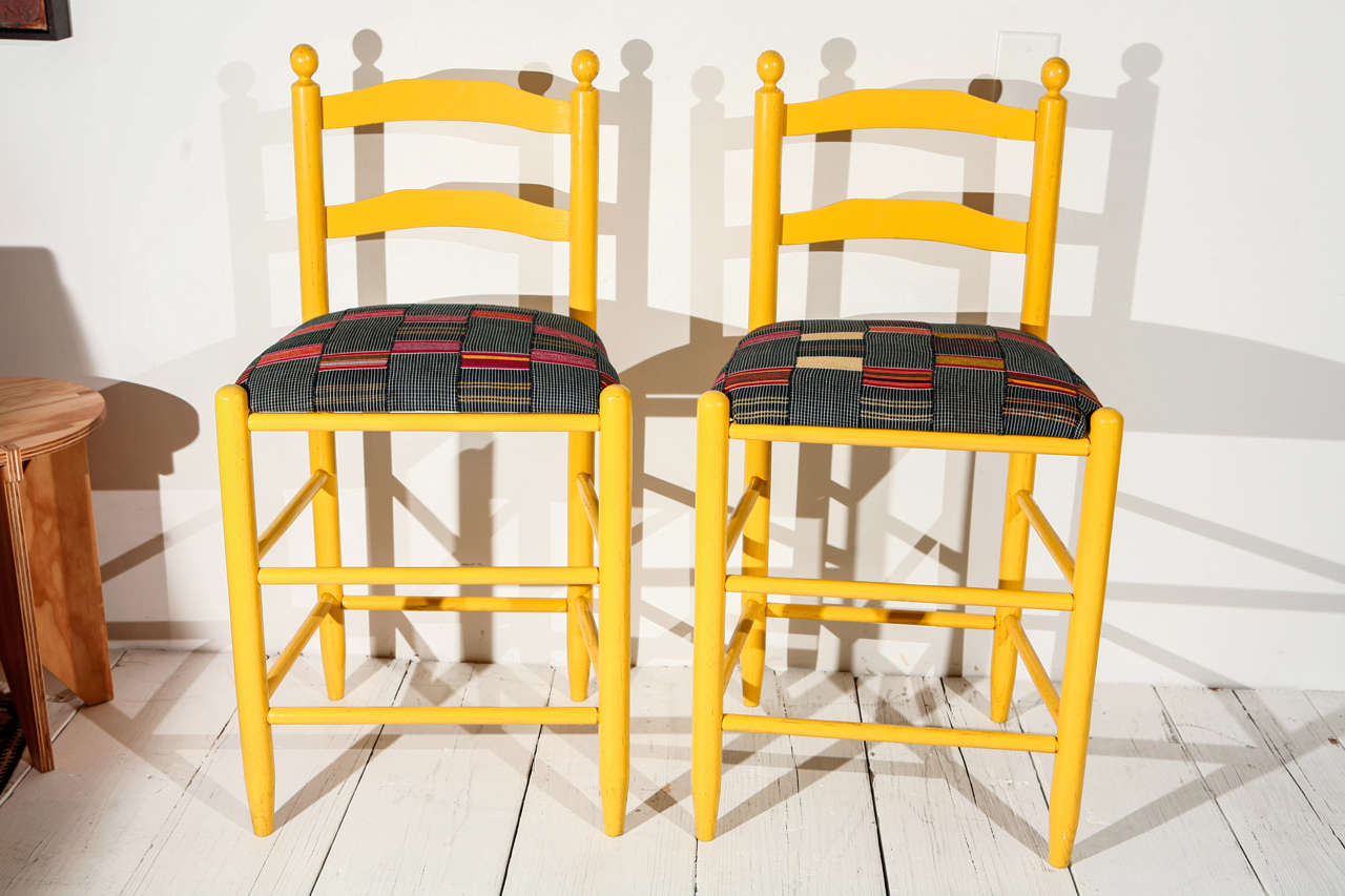 Bold yellow stools with newly reupholstered graphic African textile seats. Sold individually.