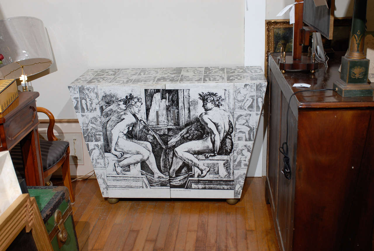 Decoupage two door cabinet with black and white neoclassical figures by artist James Randall Chumbley.  The angular cabinet rests on gilded ball feet and has a black painted interior.