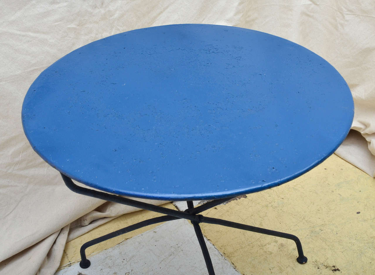 French blue painted iron round garden folding table with three scissor action legs, curving inward at base terminating on coin shaped feet. Great as a lamp or end table.