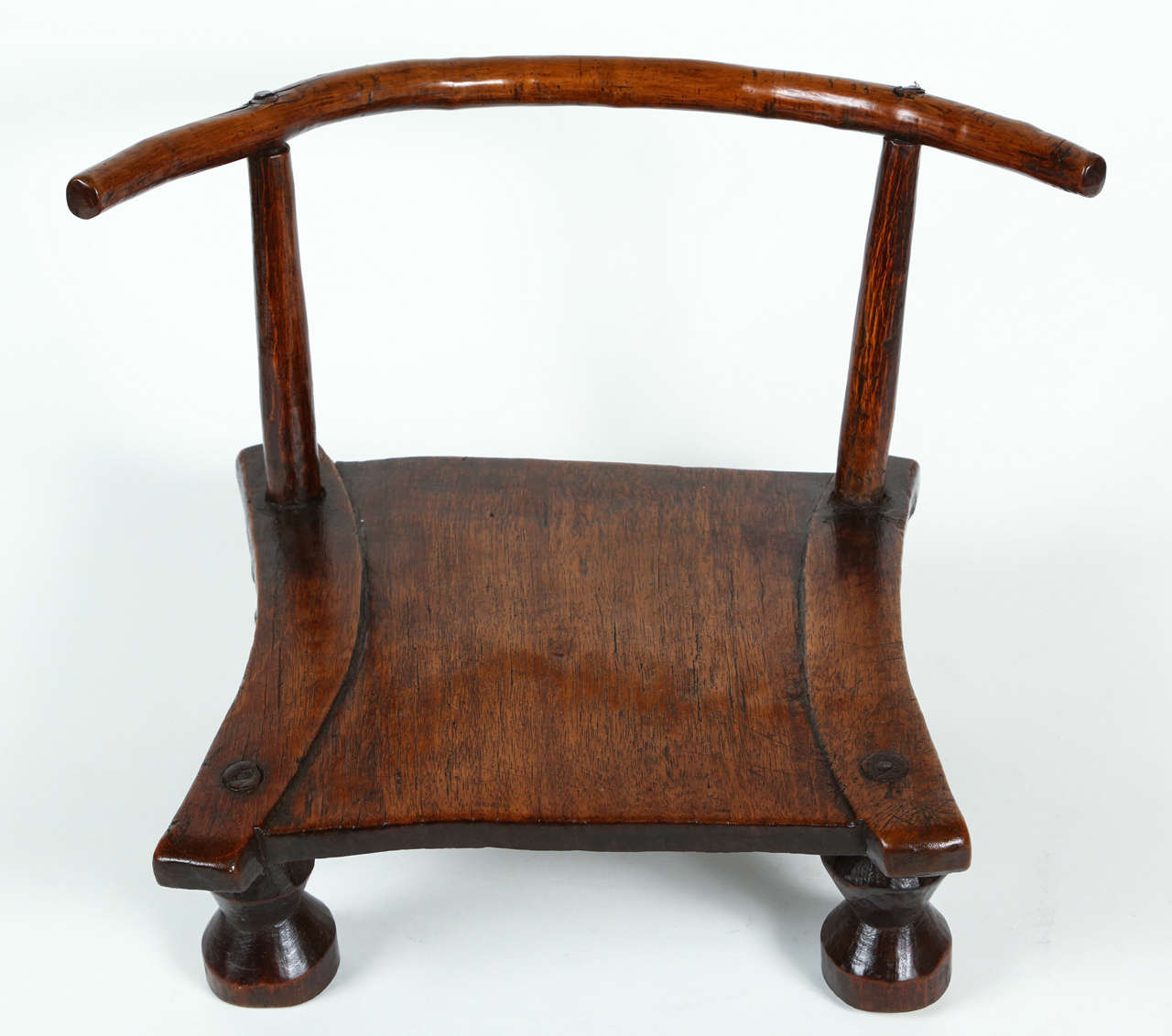 A hand-carved, small, low chair from the Dan tribe known as a grandfather's chair. These small chairs are usually part of the household effects of a distinguished family and are regarded as private property, which one would have to ask permission to