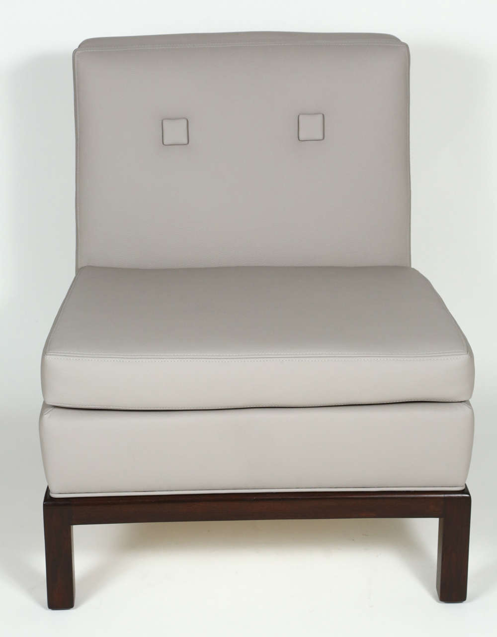 An elegant pair of slipper chairs, custom designed and made by Everett Sebring. Newly upholstered in pebbled warm grey leather, the chairs feature a dark walnut base and a handle detail on the chair back. These chairs were custom designed for Mrs.