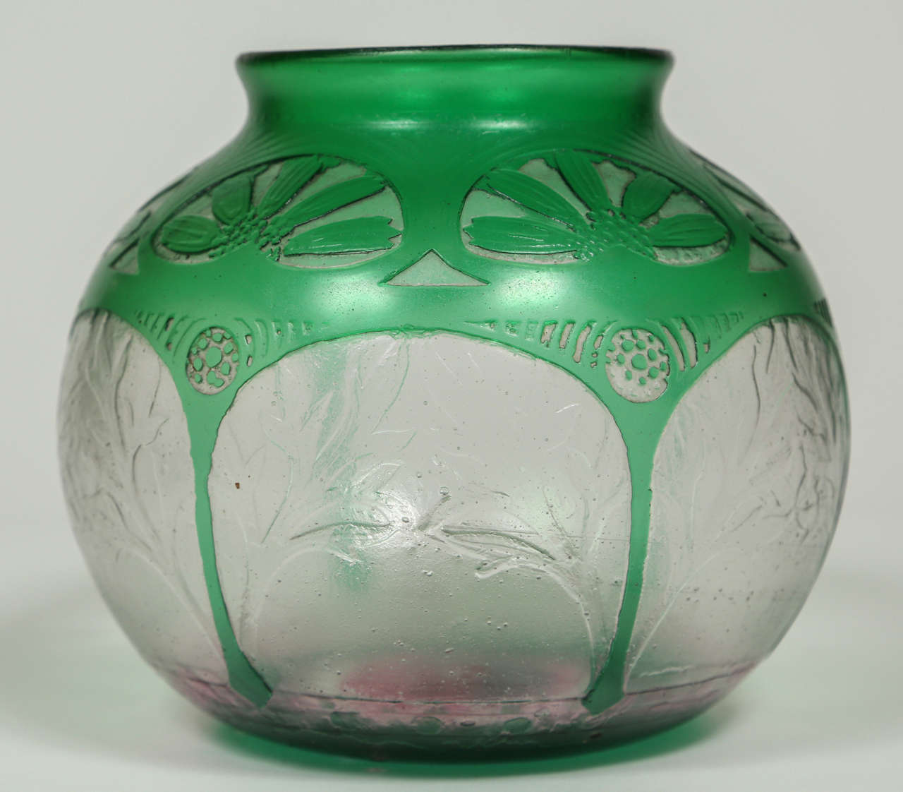 A lovely Art Deco acid etched Daum glass vase with a beautiful green etched through to the clear below with a fabulous design of stylized leaves and flowers. The bottom of the vase also has a faint layer of pink glass over the clear glass. The 