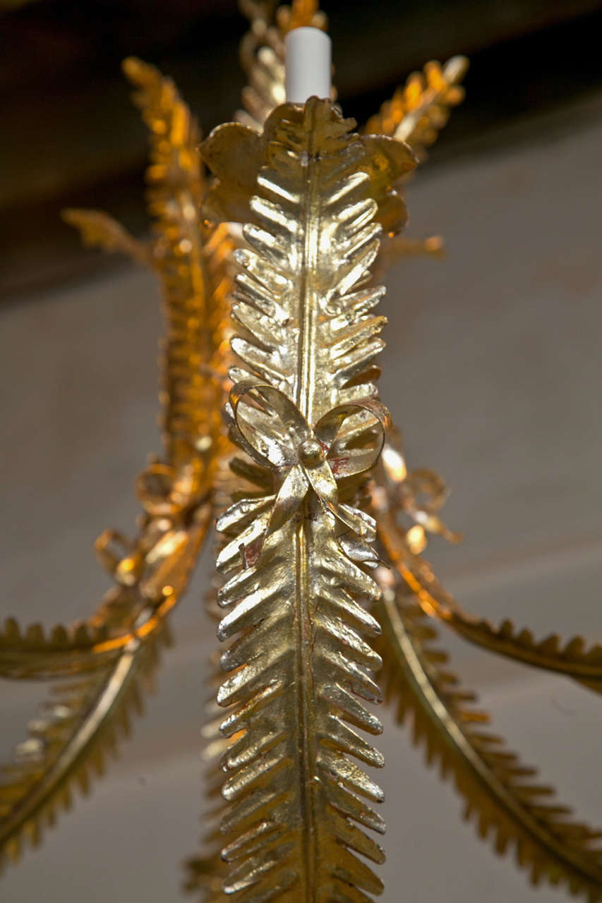 Pair of elegant Hollywood Regency style, leaf-form chandeliers, possibly from 1970s. Overall decorated with gold-leaf, each having six arms.