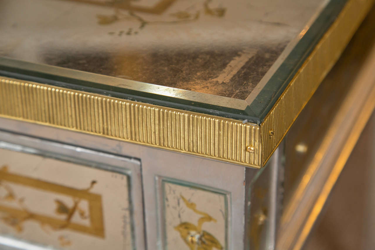An alluring French Louis XVI style silver-gilt burea plat of unique details, circa 1960s, decorated with verre églomisé gilded glass veneer depicting grape vine pattern all surround, the rectangular top over a frieze fitted with three drawers, each