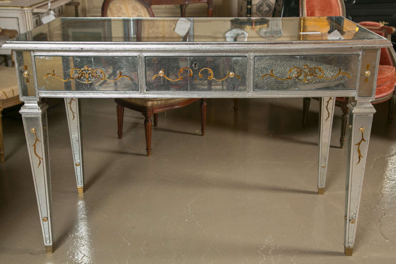 Finest Hollywood Regency style Verre Églomisée mirrored desk - vanity by Maison Jansen. This solid wooden desk with tapering legs sitting on bronze sabots and having bronze mirror supports. The overall double silver leaf design having gilt gold