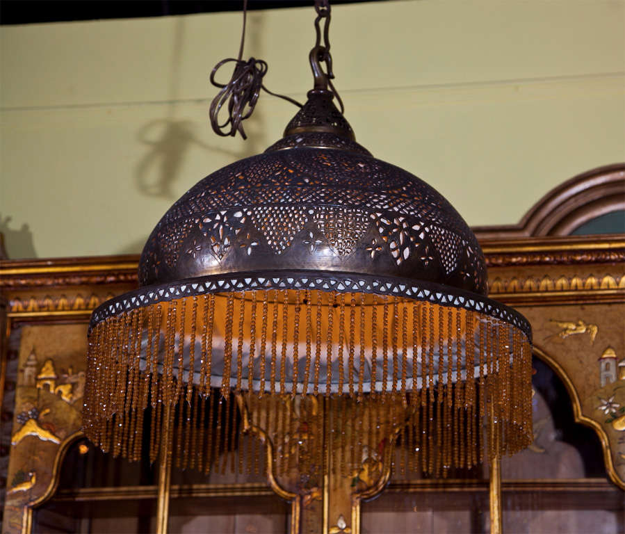 A pierced brass Moorish chandelier in the style of Alberto Pinto, delicately hand crafted & chiseled with fine filigree design and beaded skirt.