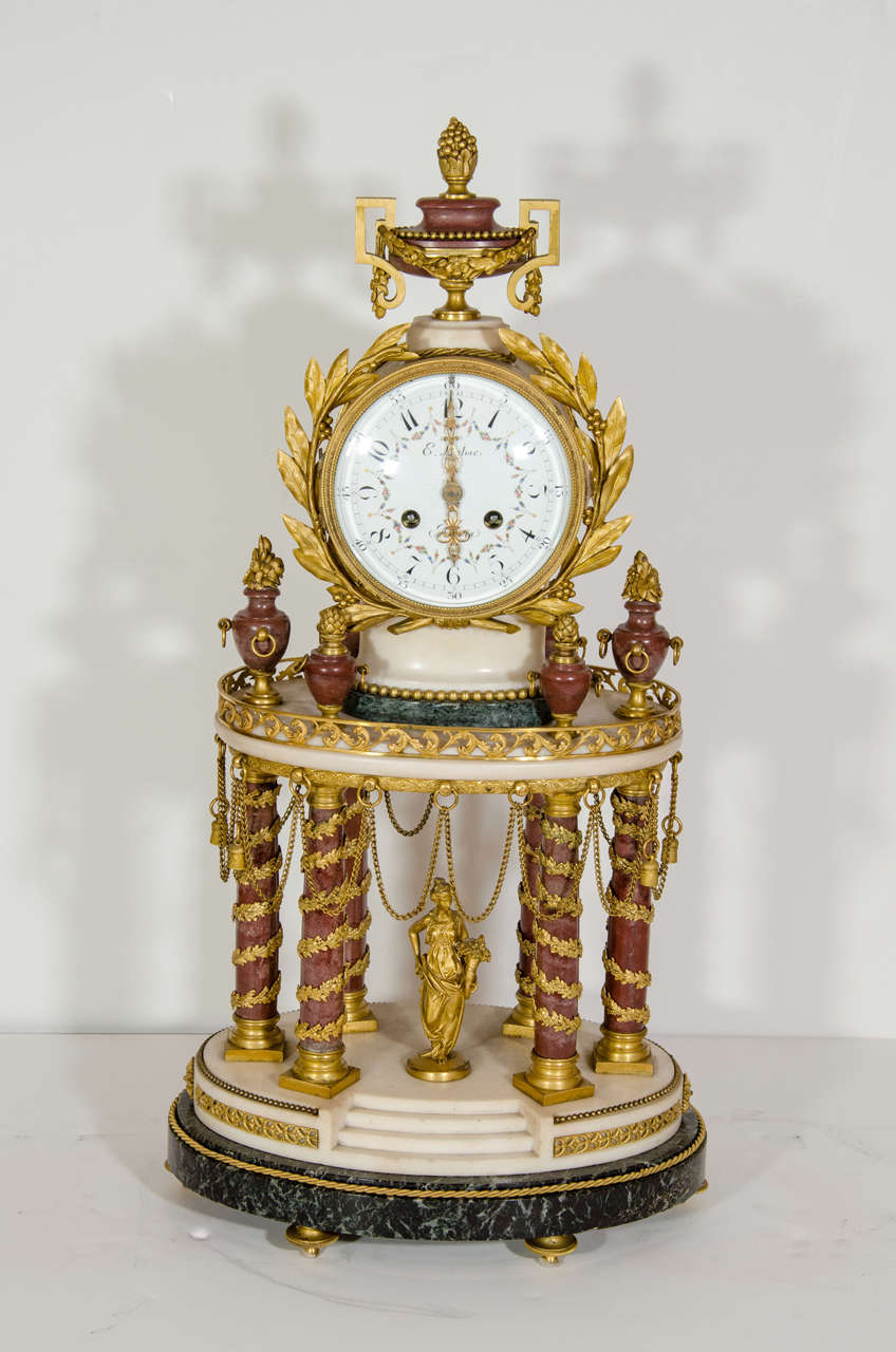 An impressive and very unusual Antique French Louis XVI style figural mantel clock composed of gilt bronze, white marble, rouge marble and dark green marble signed on the enamel dial E. Lemoine à Paris. The clock’s form is that of a classical temple