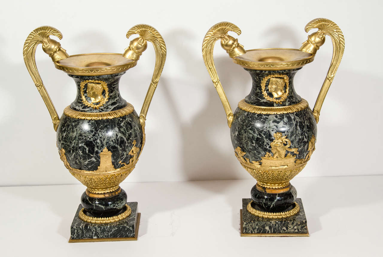 A Pair of Unusual Large Antique French Empire gilt bronze and hand carved dark green marble double handled Military urns of great detail and craftsmanship. The main body of this pair of unique urns are made of hand carved dark green marble, further
