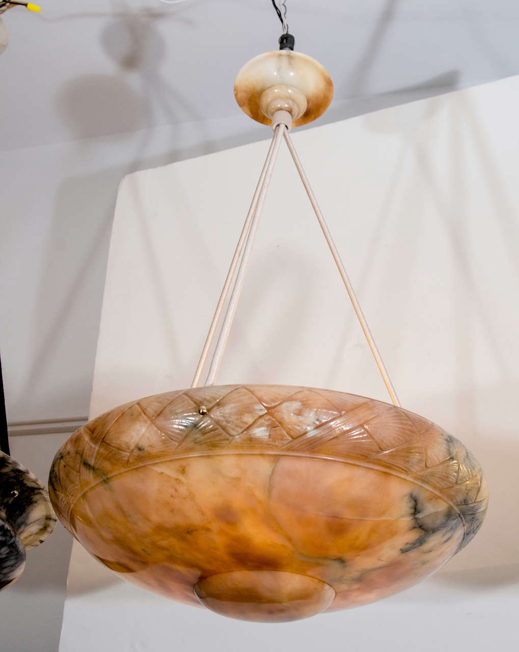 A tortoise toned neoclassical fixture with a rounded, carved band, deep mineral veining mingled with patches of crystal and an unusual canopy of matching alabaster.