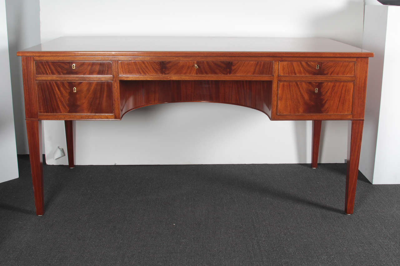 A Danish mahogany writing desk by Frits Henningsen, with a solid mahogany top, above three frieze drawers and two side drawers, a curved knee-hole panel, raised on square tapered legs.

Frits Henningsen - Danish designer and cabinet maker working