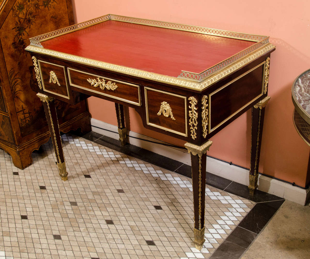A very fine French Acajou Bureau Plat with red finished writing surface,  pierced bronze gallery and trim, bronze mounts and square tapered legs.