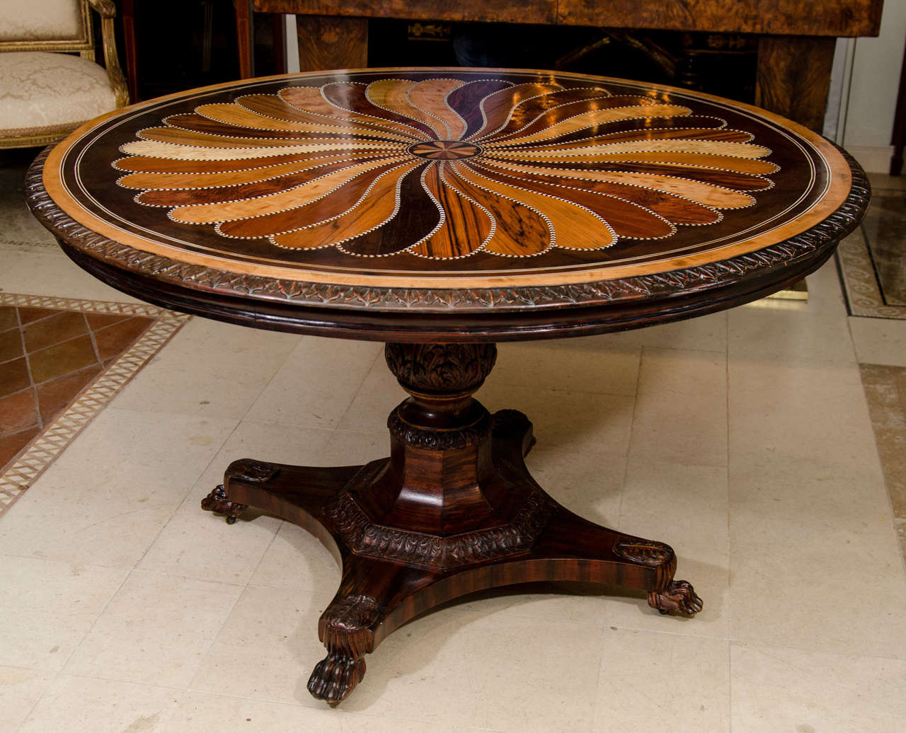 A rare Anglo-Indian Ceylonese specimen wood inlaid center table with spiraling petal motif and a leaftip carved edge, the pedestal with paw foot base.