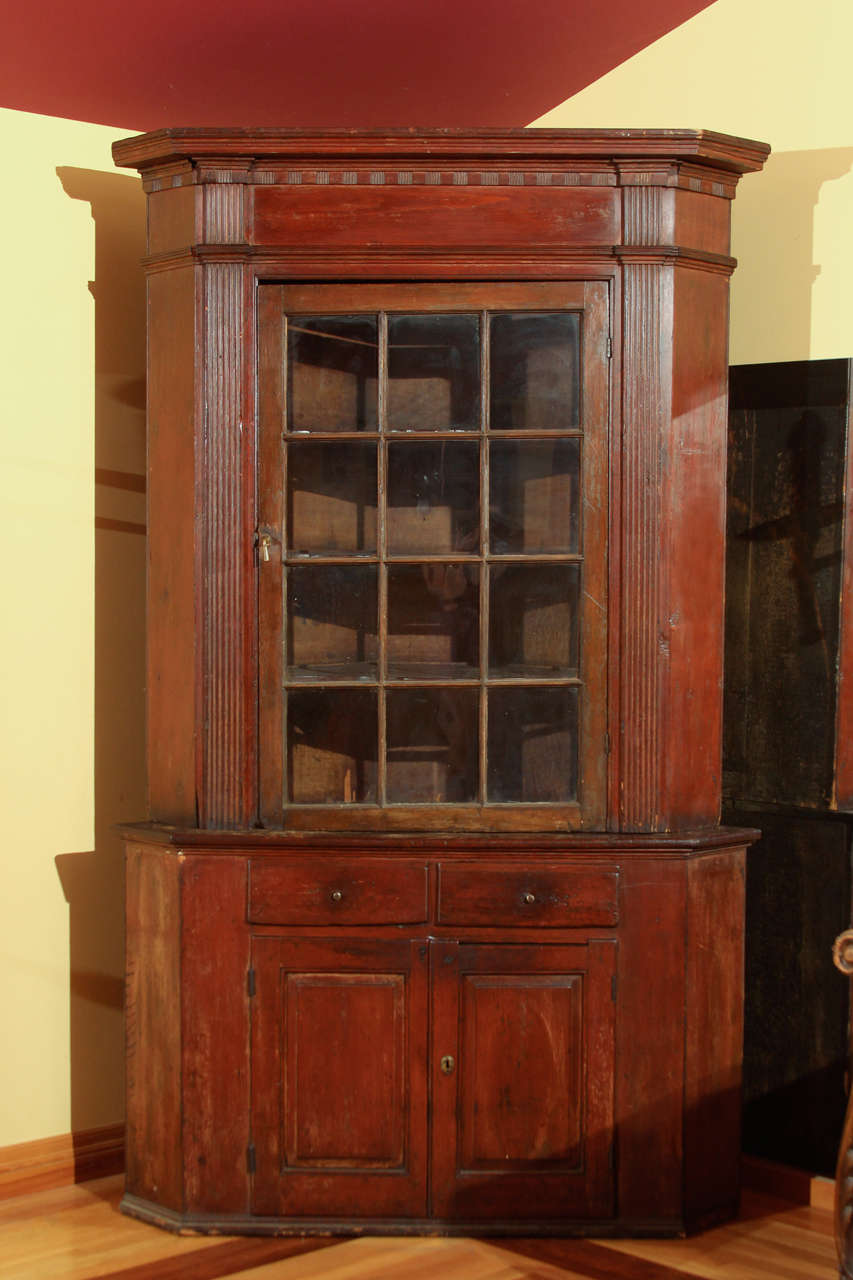 American 18th Century Corner Cupboard

This is a large American pine corner cupboard with the original finish.

Key features include 12 old wavy panes of glass, carved crown and reeded columns flanking each side of the door.  

Inside the top