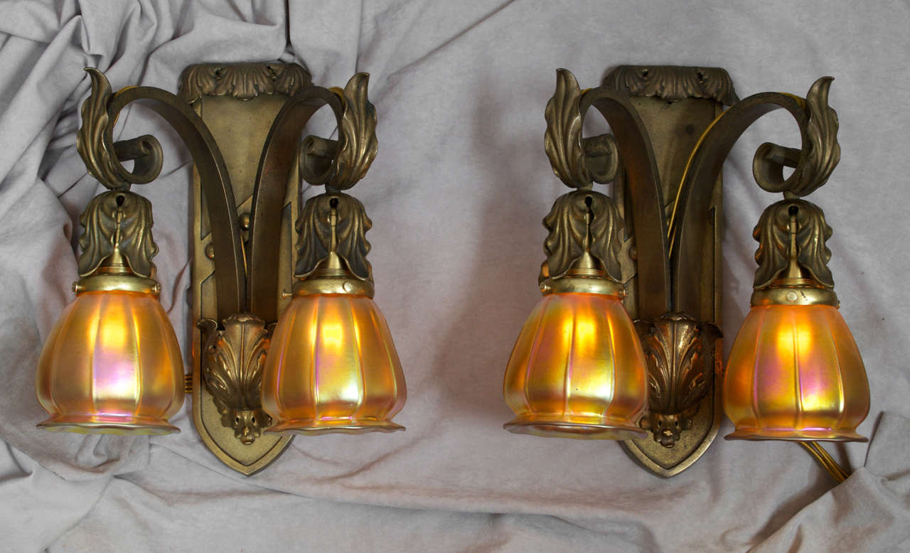 Here is a very high quality pair of cast bronze sconces with Steuben glass shades. The metal work is of the highest quality casting; nothing is cheap or flimsy. The glass shades have that wonderful iridescence and were handblown by the Steuben