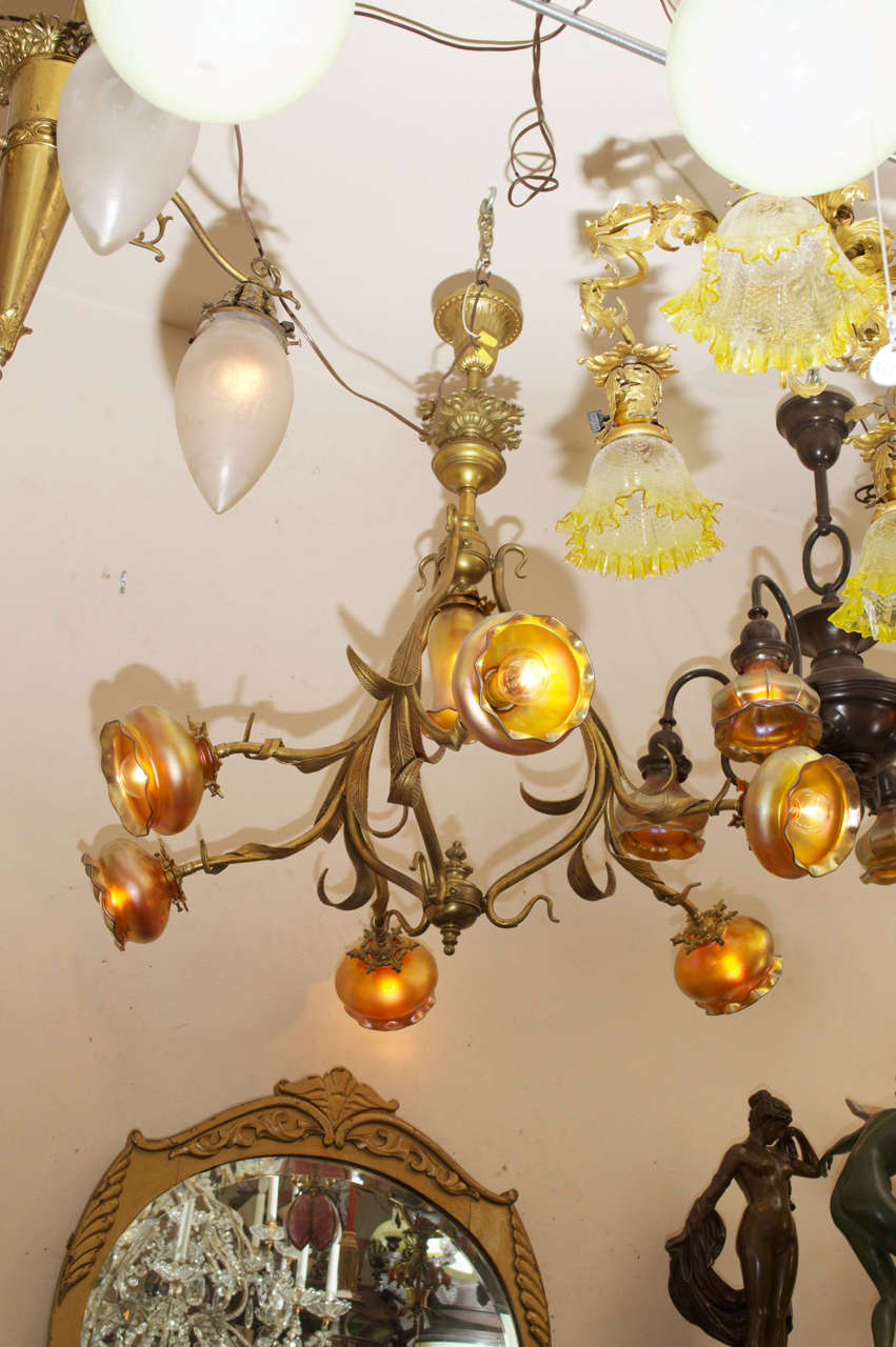 This extremely sinewy gilt bronze chandelier is a fine example of the grace and beauty of Art Nouveau. The handblown shades are there to add to the richness of this dynamic package. This is a very special fixture. The chandelier is French; the
