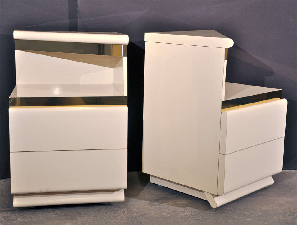 Each nightstand, made of formica with brass trims, has two slide out drawers in the lower section of its body. An additional shelf is located on the top of the nightstand, which is slanted to an angle forming a right triangle from the top view. This