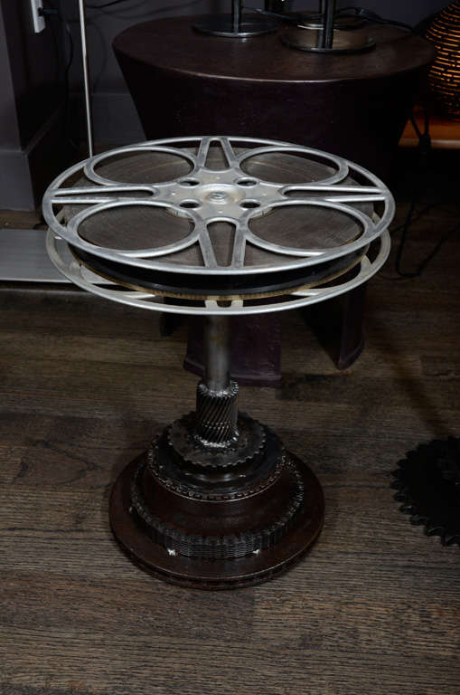 Unique industrial side table made with reclaimed 35mm movie film reels from the 1940’s and various gears as a base. With steel tubes that slide together this adjustable side table ranges in height from 18 to 26 inches.