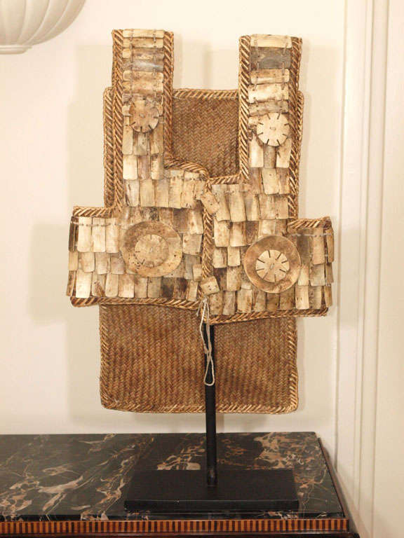 Vest in woven raffia with bone ornamentation, now mounted to custom iron stand; base measures 12 x 6