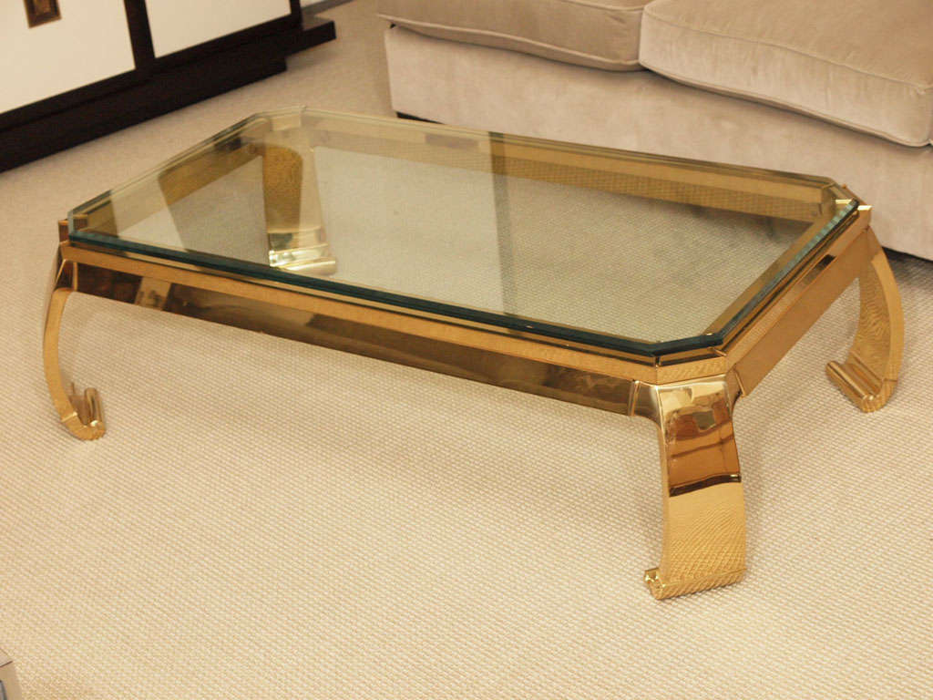 Rectangular table in heavy brass with in-curving legs and chamfered corners; conforming beveled glass plate measuring 26 x 47