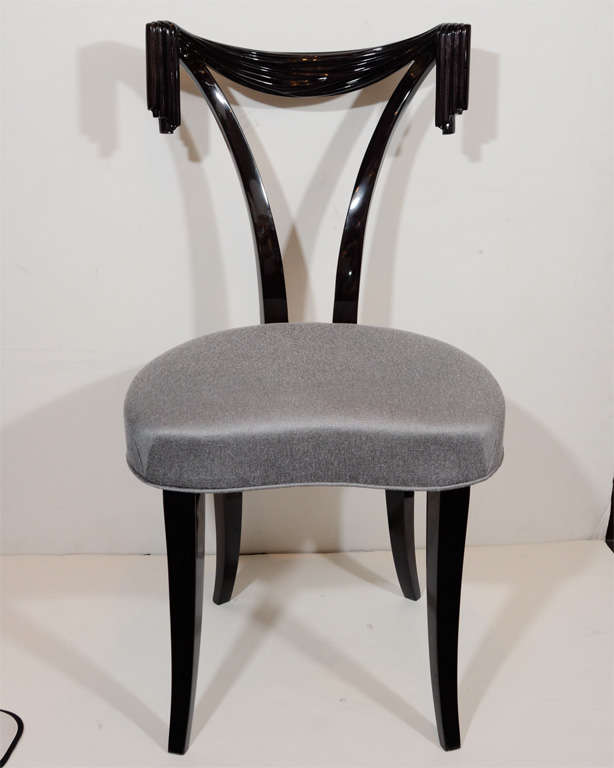 A 1940's occasional or vanity chair with hand carved draped back design and plunging back details in ebonized walnut. It has been mint restored and newly upholstered in a metallic  sharkskin fabric.
