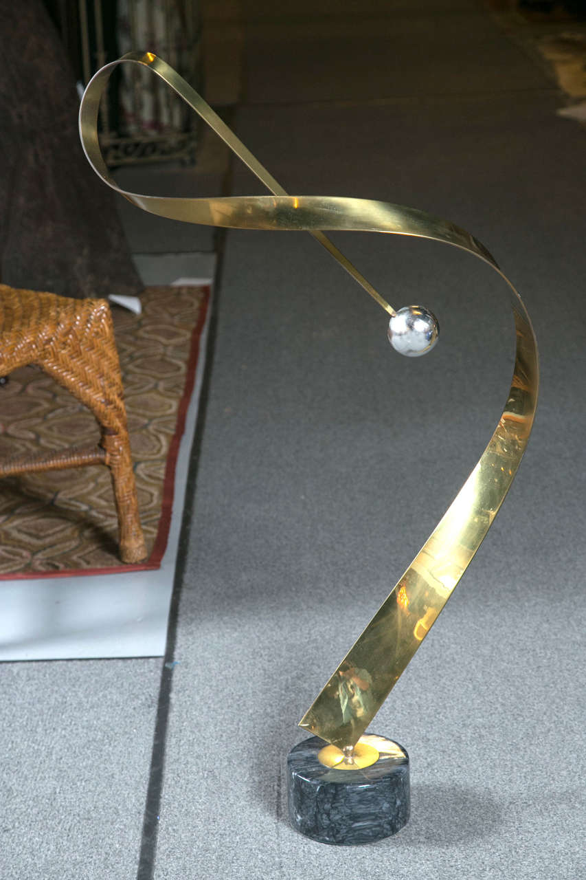 Twisting brass sculpture on a marble base.