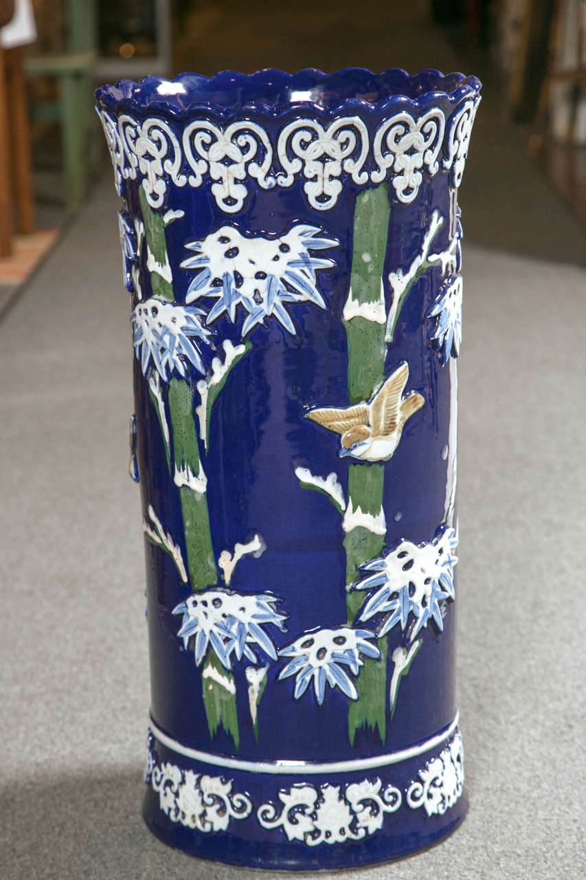 Japanese ceramic circular form umbrella stand.  Lustrous cobalt blue glaze.  Raised birds and flower decoration.  Raised flying swallows.