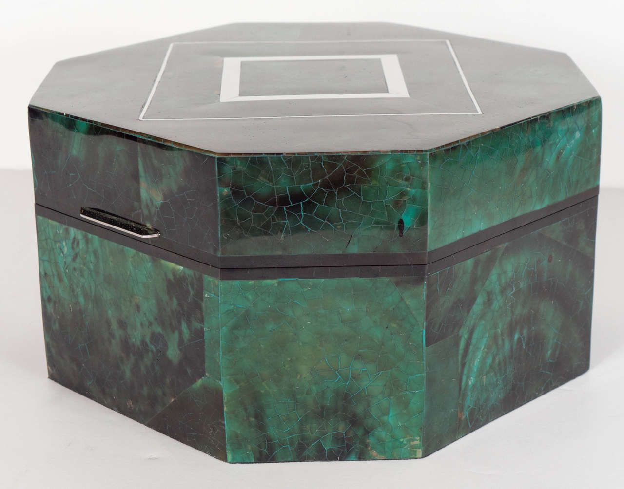 This ultra chic octagon shaped box is comprised of overlay dyed Penshell in a deep, rich Emerald color.  The box opens with a silvered sleek streamlined handle and has a black lacquer trim where that outlines the top and bottom edges of the boxes