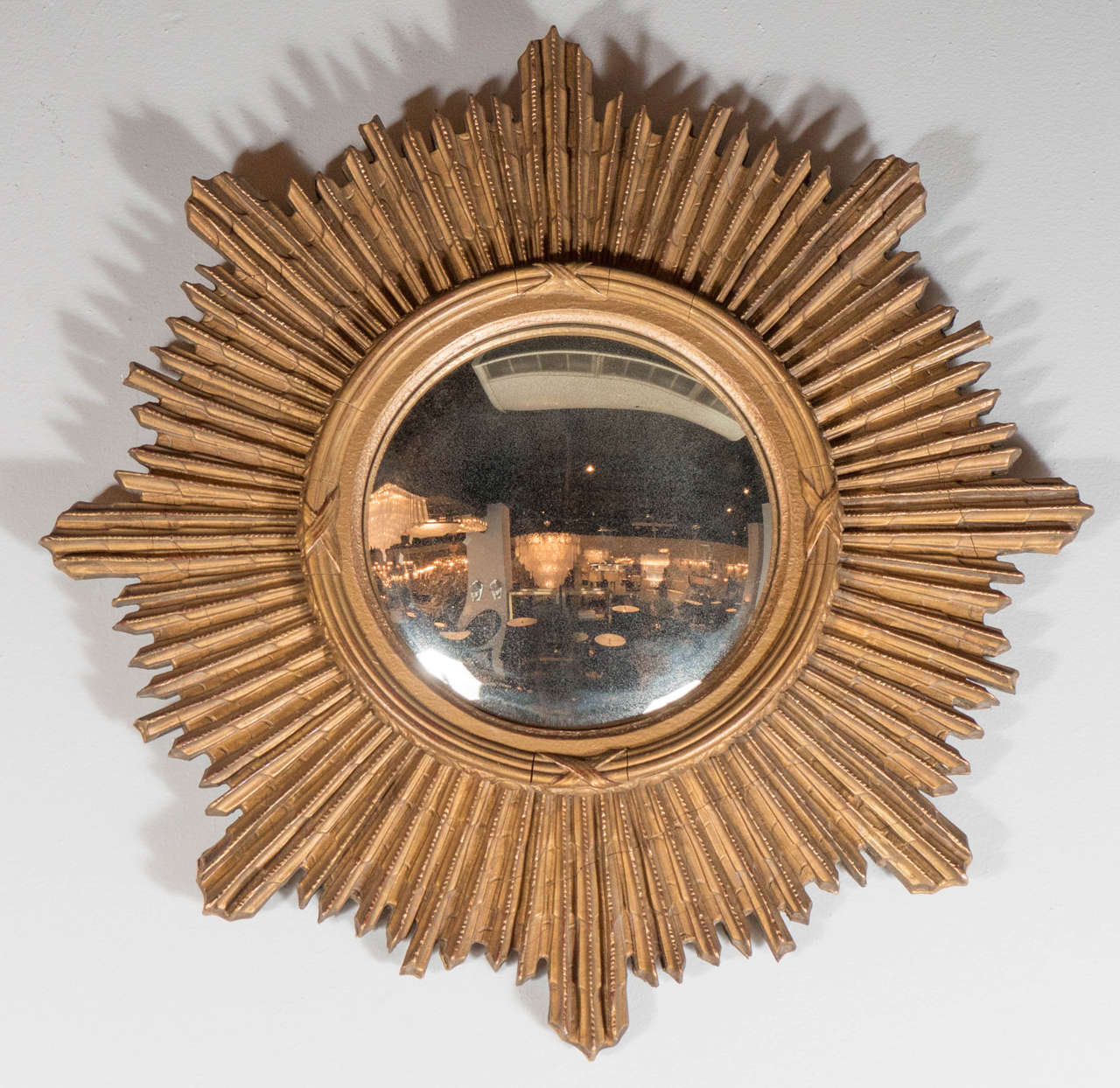 This exceptional Art Deco mirror features a sumptuous gilded starburst design with a convex antique mercury glass mirror. Great stylized Art Deco detailing.
