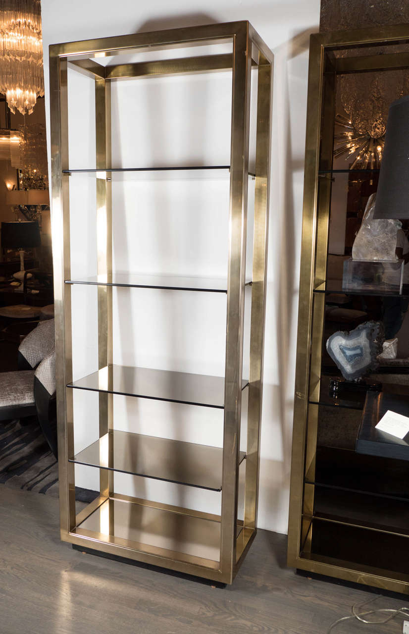 This exceptional Mid-Century Modernist etagere by Mastercraft features a brass design base fame with 5 smoked glass shelves. This pair can be sold as a singles for $4,475 each. These are in excellent condition.