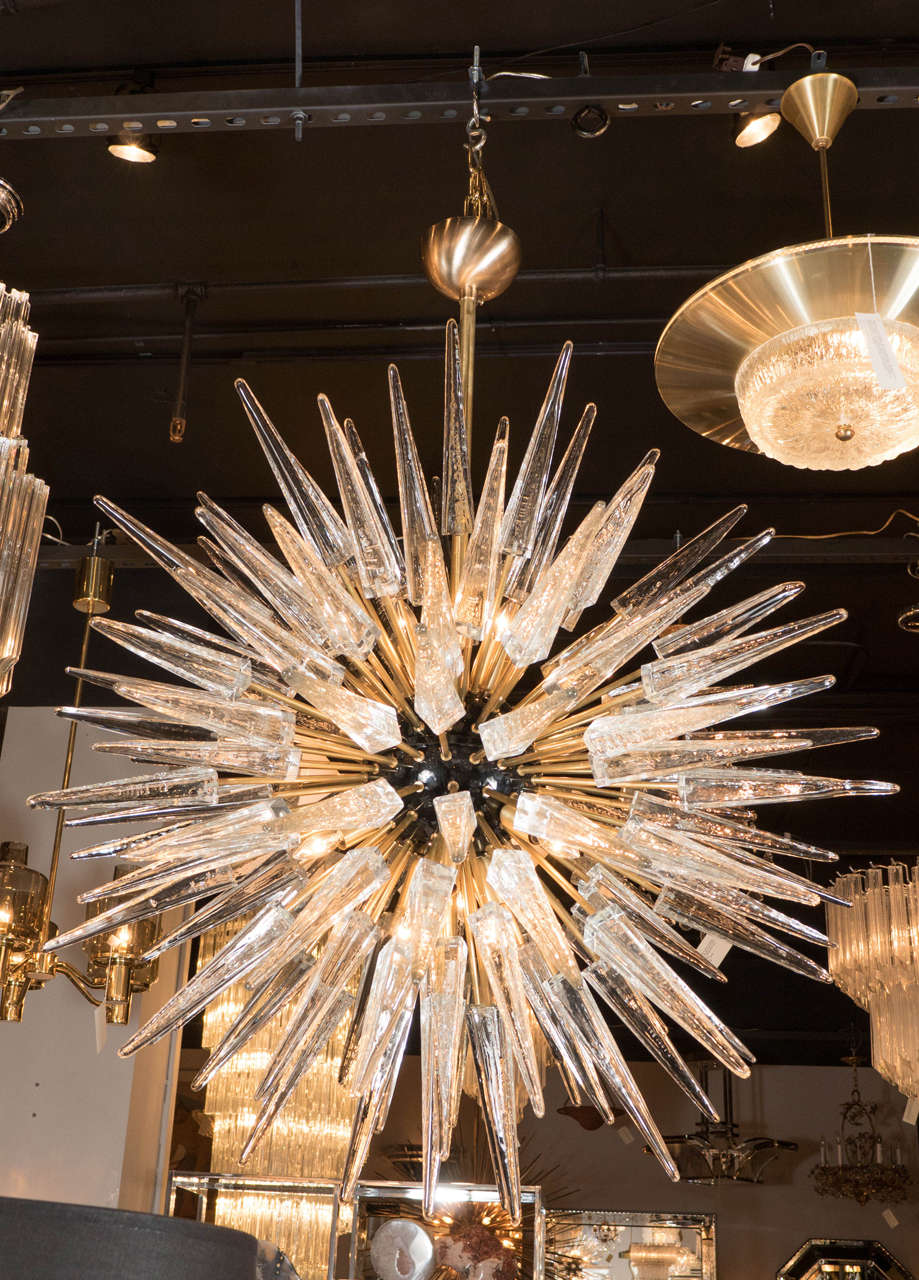 An impressive spiked Sputnik chandelier that features a black enamel spherical center that boosts twelve-candelabra based bulbs. This chandelier has numerous brass rods that emanate from its black enamel center that alternate at two different