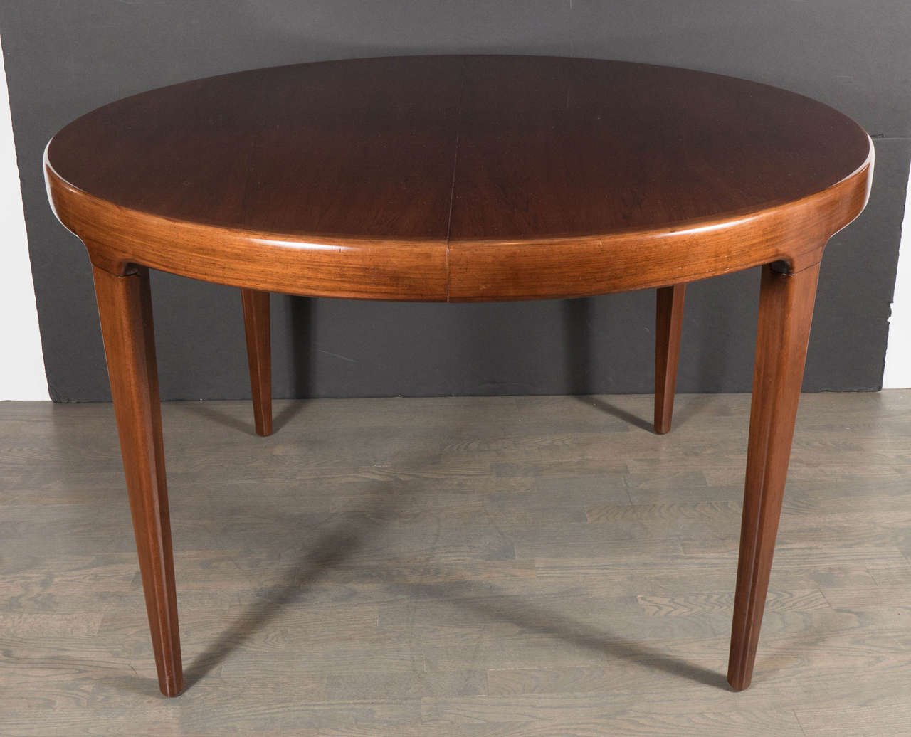 Sophisticated Mid-Century Modernist dining table in the manner of  Vladimir Kagan in bookmatched walnut with one extension leaf. This ultra-chic Mid-Century dining table features a tabletop in bookmatched walnut in a hand-rubbed finish that really
