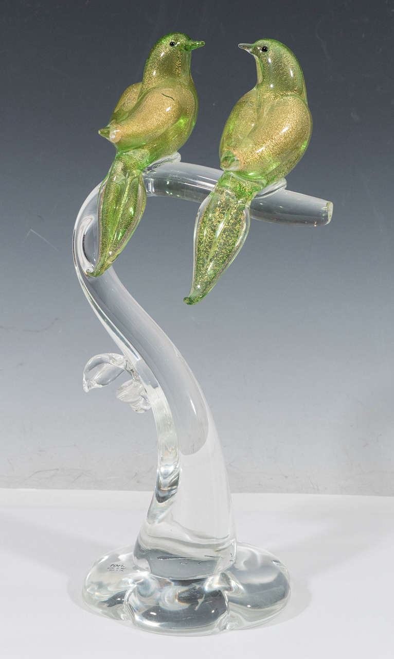 A vintage Murano glass sculpture, produced circa 1960's, with two birds in green, infused with flecks of 14K gold, perching on a curved, clear glass branch. Markings include the remains of the original sticker [Formia Vetri di Murano/Made in Italy]