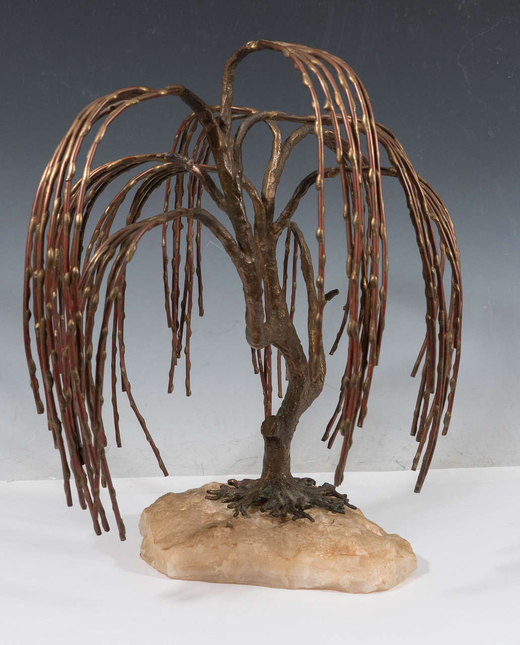 A vintage, sculptural weeping willow by artist Brian Bijan, produced circa 1960-1970, hand soldered in mixed metal, with bronze tree form, copper branches and brass drops, fixed above a raw quartz stone base. Markings include serial number 69-250,