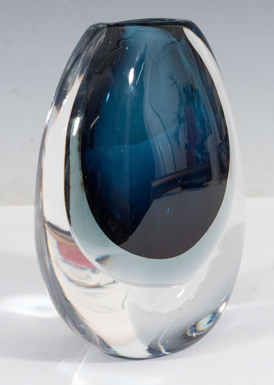 A vintage glass vase, produced in Sweden, circa 1950s by Vicke Lindstrand for Kosta Boda, in rich blue color, encased in pale gray layer, and surrounded by clear glass. Markings include signature [Kosta/ 44 18 25], engraved to the bottom of the