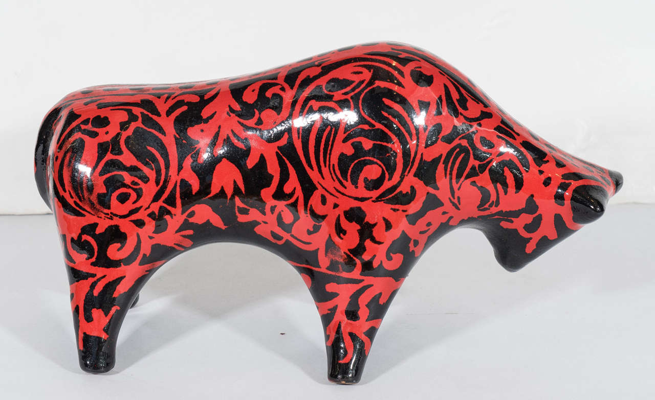 A vintage sculptural ceramic bull, produced in Italy, circa 1960s by Bitossi, designed by Alvino Bagni, with unusual glaze over black, detailed with red scroll work patterns. Markings include [Italy] incised to bottom of front left foot. Very good