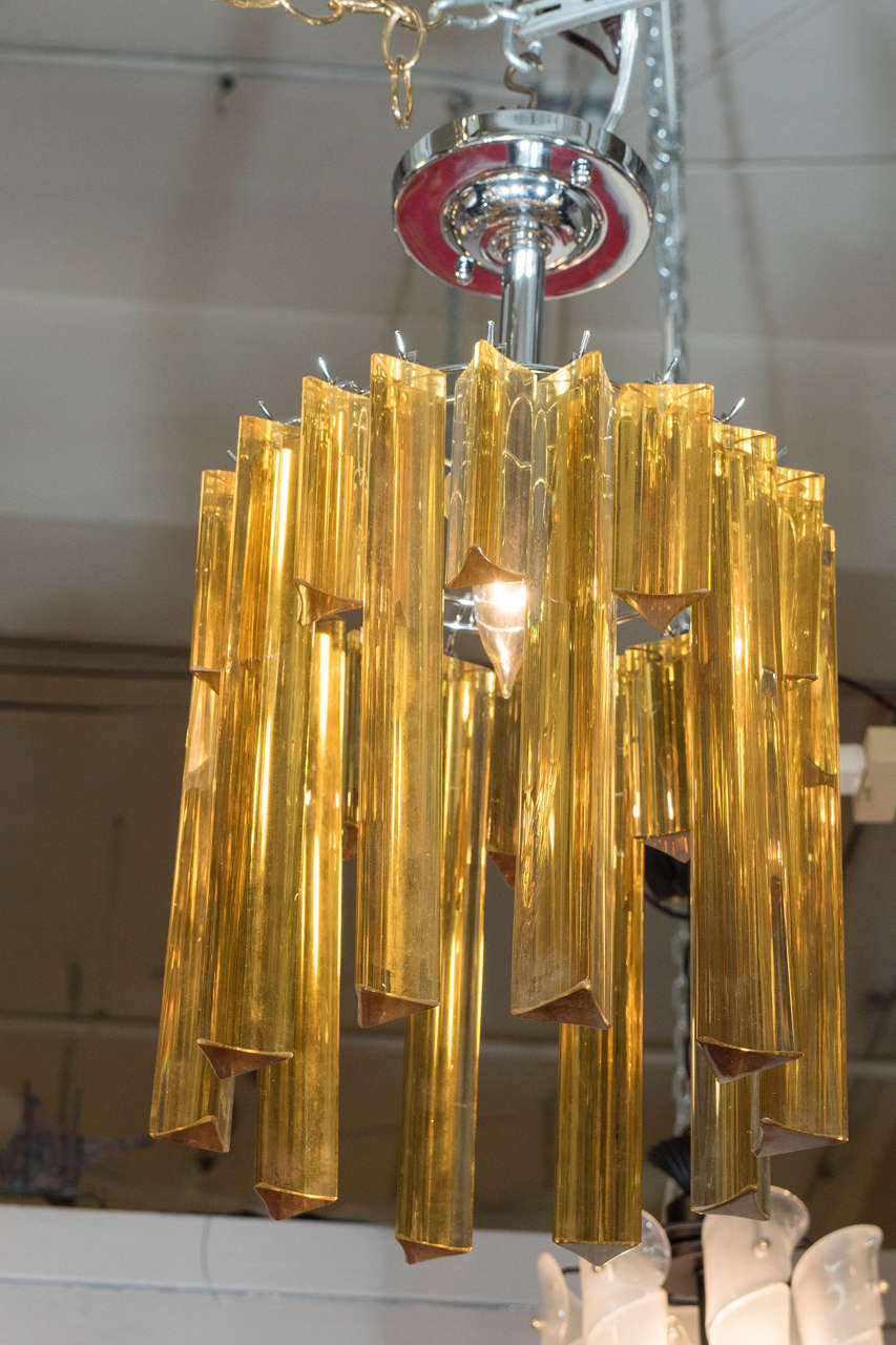 Lustre italien vintage, produit dans le style de Venini, vers les années 1970, avec des prismes tryritiques ambrés en quinconce de différentes longueurs, suspendus à un cadre central en métal et à une plaque de plafond circulaire. Nouvellement