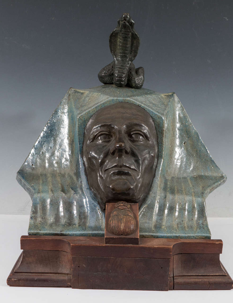 A highly unique antique sculpture of an Egyptian funerary mask, possibly French in origin, produced early 1900s, with classically rendered bronze face, inset against a glazed green and blue terracotta headdress, with a coiling cobra in bronze as