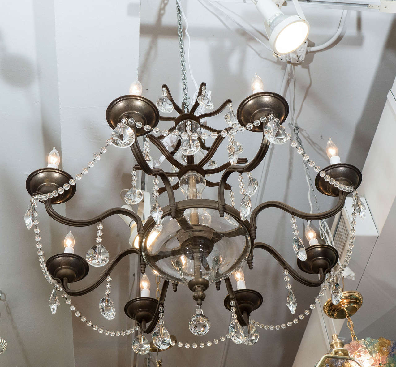 A vintage chandelier with iron frame, trimmed with Sciolari crystals, with central rod, surrounded by two baluster form glass bulbs, beset by two levels of extending, curved beams, each with beading and drops, suspending eight scroll arms, each with